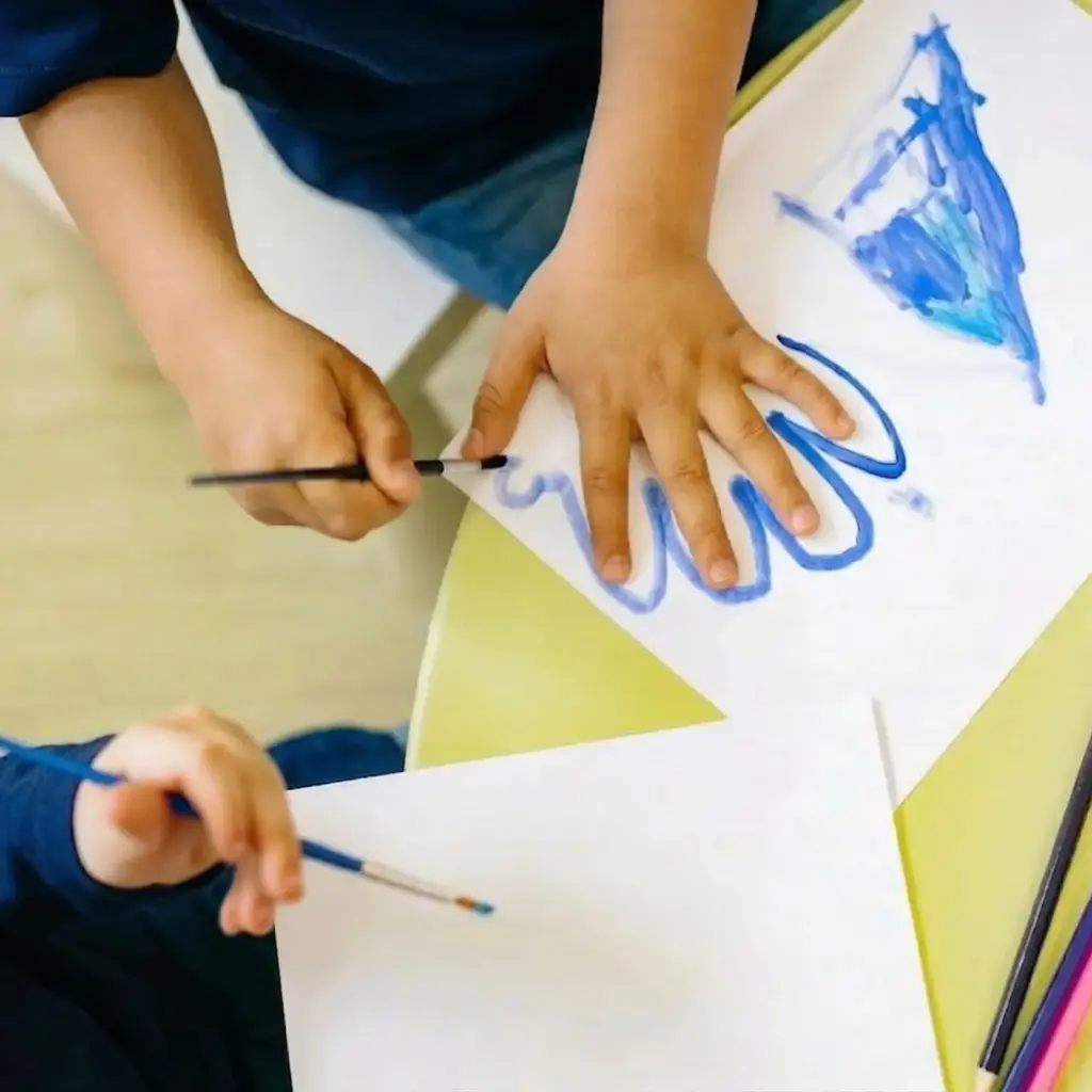 Kid tracing his hand with a paintbrush
